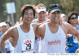 Jake Shimabukuro with best friend Jeff Lau and running coach Rick Varley (in back) cross the finish line at the 34th annual Honolulu Marathon