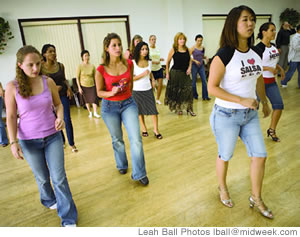 The author, left, Wanda Harris, in red, and instructor Amy Tomita, right, practice their salsa steps