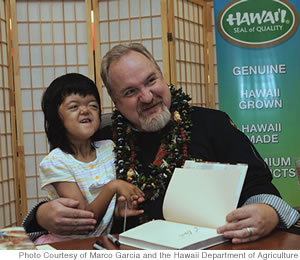 Easter Seals Hawaii participant Maile Ogata receives a hug and signed cookbook 