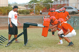 Kahuku outside linebacker coach Wes Tufaga guides the players during practice
