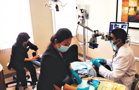 Dr. Farid Shaikh attends to a patient with the help of massage therapist Keiko Katoku (far left) and dental assistant Kim Souza