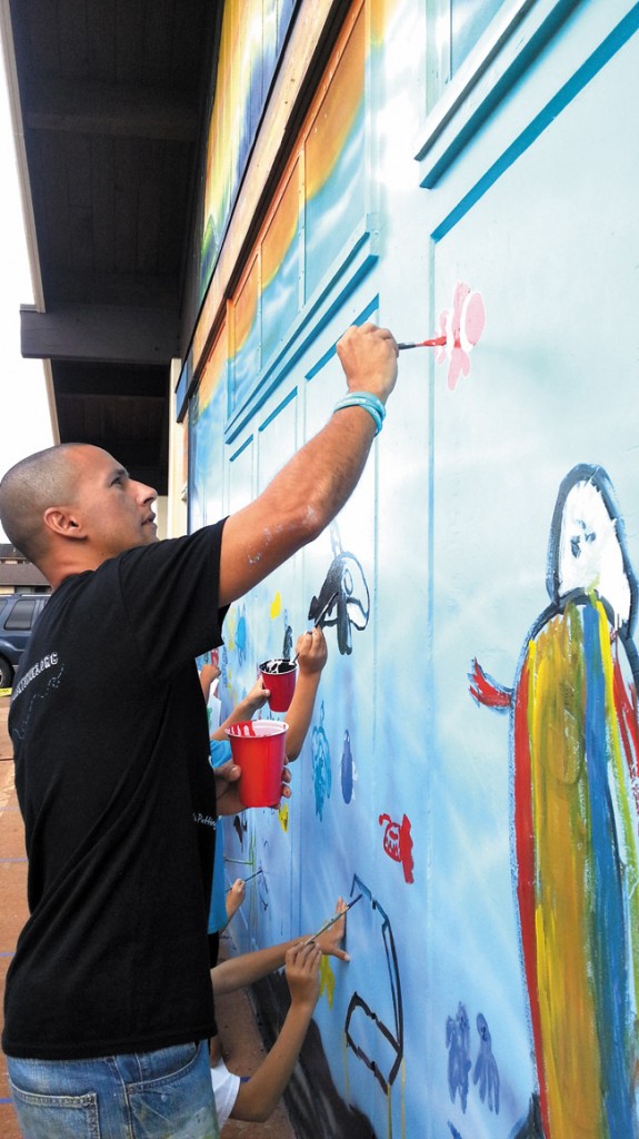 Hilton Alves joins Kanoelani artists as they personalize their new mural. Photo from Bryan Wyland. 