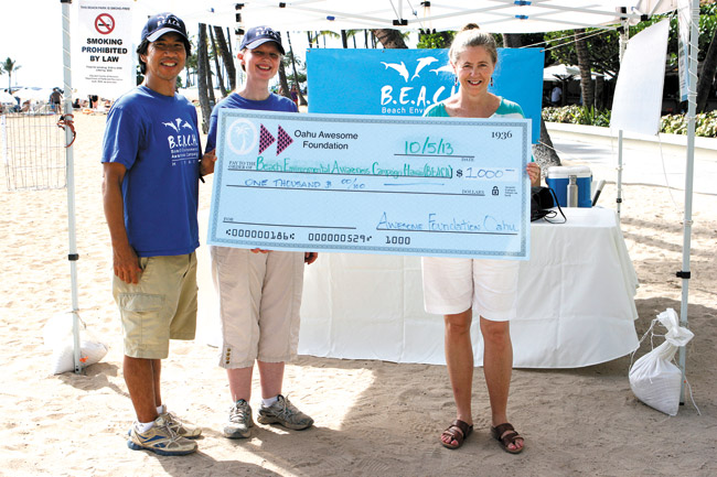 Dean Otsuki and Suzanne Frazer, co-founders of Beach Environmental Awareness Campaign Hawaii, accept a $1,000 grant from Awesome Foundation of Oahu representative Donna Ambrose (right). Photo courtesy of B.E.A.C.H. 
