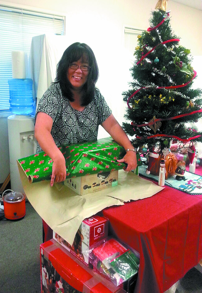 Jan Harada wraps up Christmas gifts for the Adopt A Family program. Photo courtesy Helping Hands Hawaii
