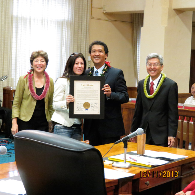 Highway Inn's Monica Toguchi receives an honorary certificate presented by Councilmembers Carol Fukunaga (far left), Ron Menor (holding certificate) and Breene Harimoto. Photo from Councilman Menor.  