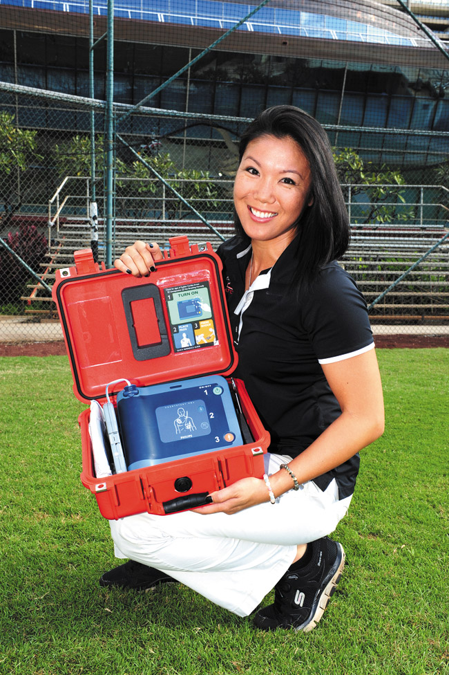 Iolani School athletic trainer Louise Inafuku with an automated external defibrillator | Nathalie Walker photo