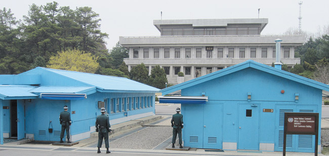 Standing near Panmunjom meeting rooms, South Korean soldiers stare at North Korean headquarters (gray cement building) as North Korean guards stare back | Bob Jones photo