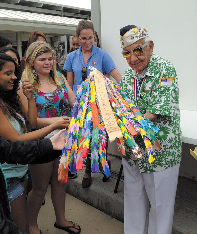 Castle High freshmen Maya Farias (left) and Maile Goldstein, and USS Arizona education coordinator Emily Pruett present the students' paper cranes to WWII veteran and Pearl Harbor survivor 'Uncle Al' Rodrigues. Photo by Shiloh Richardson Francis. 