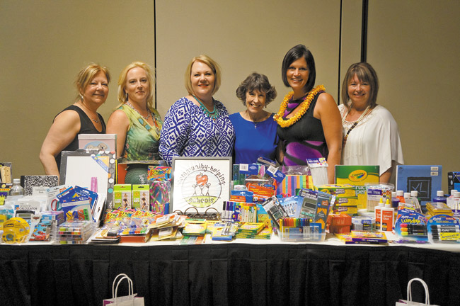 Kathie Wells (in solid blue) recently accepted gifts in Waikiki from members of the lia sophia group on behalf of Community Helping Schools. The company also donated a total of $3,331.18 to the Windward-based CHS to help fulfill teachers' wish lists here. With Wells at the presentation are lia-sophia sales representatives (from left) Johanne Bolduc, Tammy Dixon, Tracy Stewart, Marcia Cota and Denise Ouellette. Photo from Kathie Wells. 