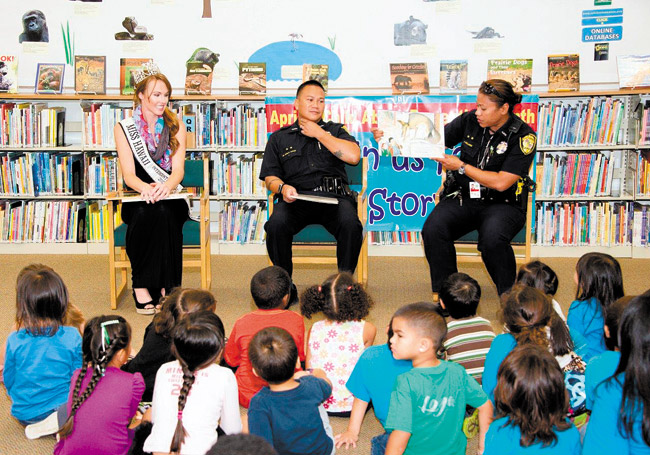 Kapolei Station-based HPD officers (from left) Shannon Dresser, Mike Dela Cruz and Jody Willard read to more than 100 keiki at Kapolei Library during Child Abuse Prevention Awareness Month. Photo from Prevent Child Abuse Hawaii. 
