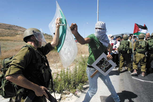 A Palestinian confronts an Israeli soldier, left, during a demonstration against Israeli military action in Gaza, near the West Bank town of Nablus, July 14. Israel began its campaign against militants in the Hamas-controlled Gaza last Tuesday, saying it was responding to heavy rocket fire from the densely populated territory. As of last Friday, Israel had launched more than 1,300 airstrikes since then, while Palestinian militants launched nearly 1,000 rockets at Israel. AP Photo/Nasser Ishtayeh