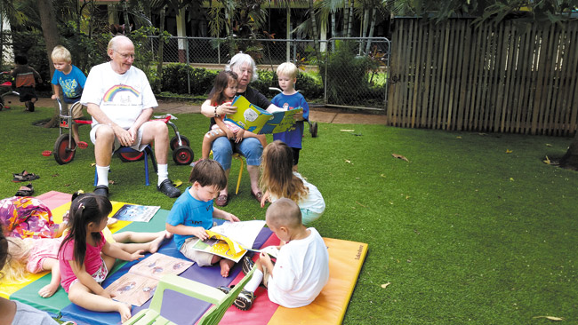 Rev. Samuel Cox and Carolyn Anderson, residents of Pohai Nani Retirement Community and newly minted 'foster grandparents,' share a somewhat intense story hour with eager little readers at Seagull School in Kailua. Photo from Seagull Schools. 
