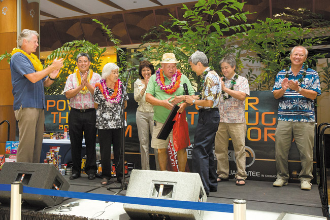 City Councilman Breene Harimoto presents 'Mayor' Herbert Pang with a plaque of recognition for his dedication to assisting other Pearlridge customers. Also pictured (from left) are Pearlridge Center general manager Fred Paine, state Rep. Mark Takai, Jane Pang, state Sen. Donna Mercado Kim, and state Reps. Roy Takumi and Gregg Takayama. Photo by Anthony Consillio, aconsillio@midweek.com. 