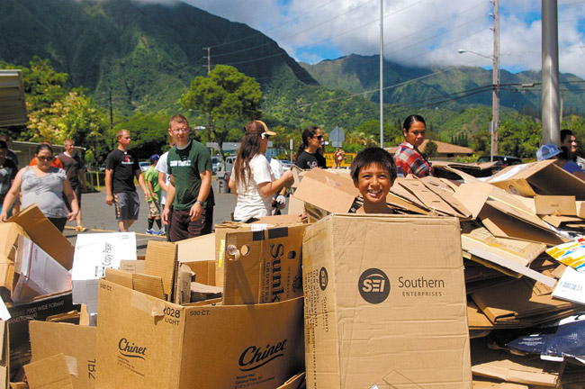 Sixth-grader Elijah Kekaula has a playful moment amid a mountain of corrugated cardboard, which was donated to Kahaluu Elementary School's Aloha 'Aina recycling drive in September. Area churches, school retirees, families and farmers — they all pitched in to clean up the community and help the school. Photo from Melanie Afualo. 