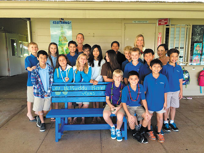 Holy Nativity School's fifth-grade class gathers around Christian Bucks (seated, left) and their classmate Caden Lombard, who partnered up to bring Bucks' Buddy Bench to the Aina Haina school. Photo from Kelly Goheen.