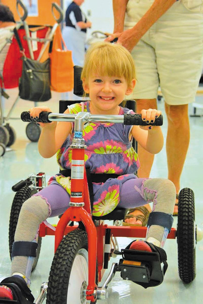Avalon Pirrone appears delighted with her new tricycle, which she received Dec. 13 during a distribution by Imua Kakau Trykes at Kailua District Park. The group provides adapted tricycles and services to help non-mobile children ‘get moving.' Photo from Angela Pirrone.
