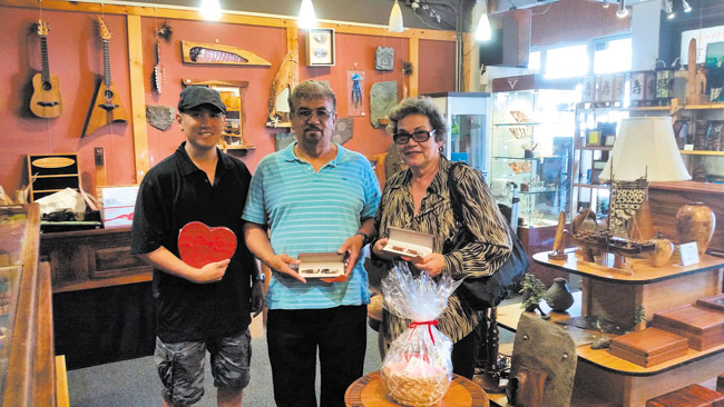 Evelyn Souza (right) wrote husband Franklin (center) a Valentine's Day letter and won Simply Wood Studios' Pen A Love Letter Contest. Pictured with the happy Kapolei couple, who received a Simply Wood Studios gift certificate for a hisand-her pen set, is studio owner Aaron Lau. Photo from Kirsten Fujitani. 