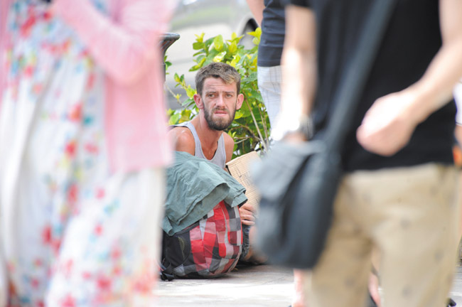 Tourists pass by a man sitting on a Waikiki sidewalk BRUCE ASATO / STAR-ADVERTISER PHOTO 