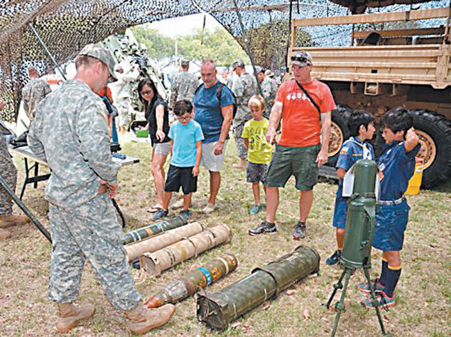 Spc. Isaac Aiken (front), a cannon crew member, explains the different types of ammunition that can be fired by a Howitzer during the 104th Boy Scouts of America Aloha Council outing at Ala Moana Beach Park. PHOTO BY SGT. CARLOS DAVIS.