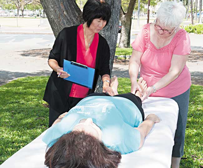 Body mapper Vicki Mauck (right) shows iFoG founder and president Annette Kam typical "lumps and bumps" found on muscles and ligaments and fibromyalgia client Stephanie Uejio. NWPhoto