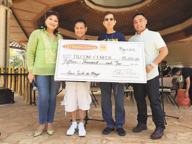 L&L president and CEO Eddie Flores Jr. (second from right) presented FilCom Center executive director Donnie Juan (second from left) with a $15,000 check May 9 during the Flores De Mayo Filipino Fiesta at Kapiolani Park. Flanking them are emcees Amelia Casamina Cabatu (left) and Glenn Sagayadoro. PHOTO FROM BRANDON DELA CRUZ.