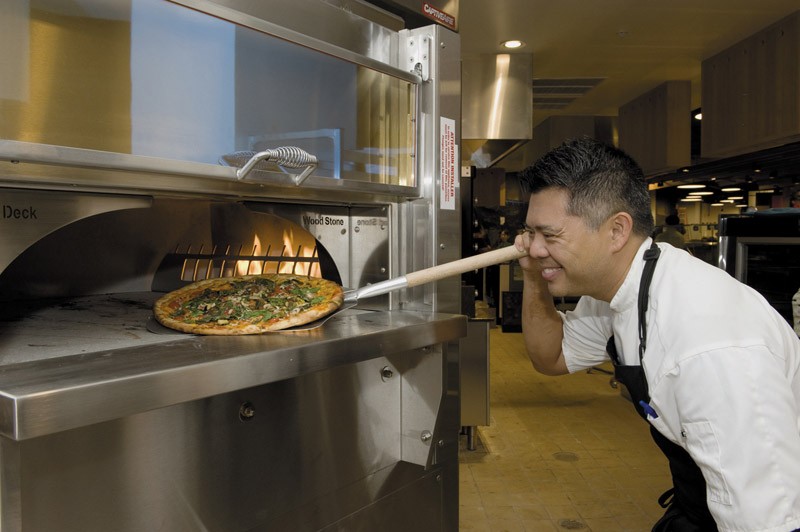 Corporate chef Keoni Chang pulls out a freshly made thin-crust Naples-style pizza  