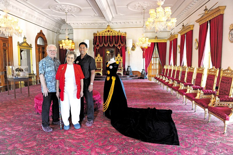 The Friends of ‘Iolani Palace board president Robbie Alm (left), founding member Beadie Dawson and executive director Kippen de Alba Chu stand in the restored throne room, next to a replica of one of Queen Kapi‘olani's famous gowns 