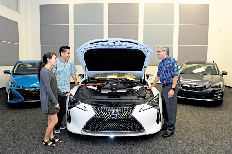Rick Ching (far right) gives a peek under the hood of the 2018 Lexus LC500H's new multistage hybrid system to Kaelyn Okuhata, Servco communications assistant, and Casey Nishimura, corporate communications manager 