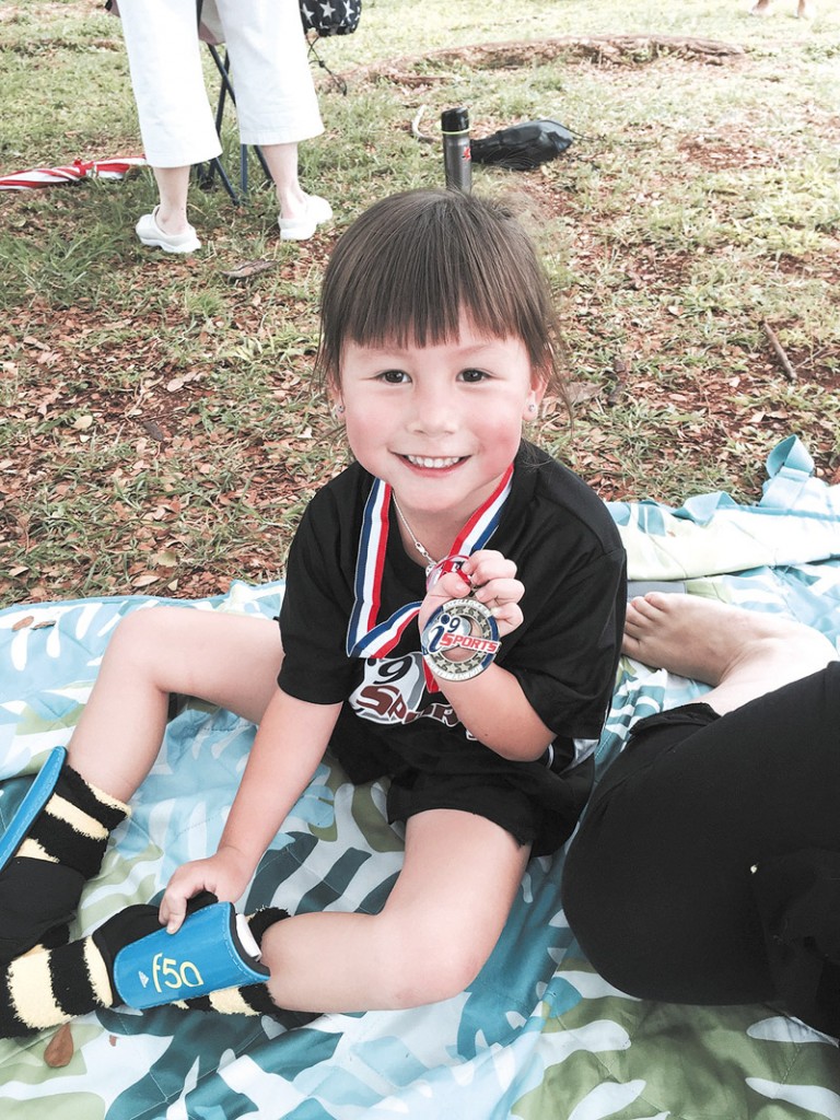 Five-year-old Liko White is all smiles after scoring a goal at her soccer game, earning a medal.
